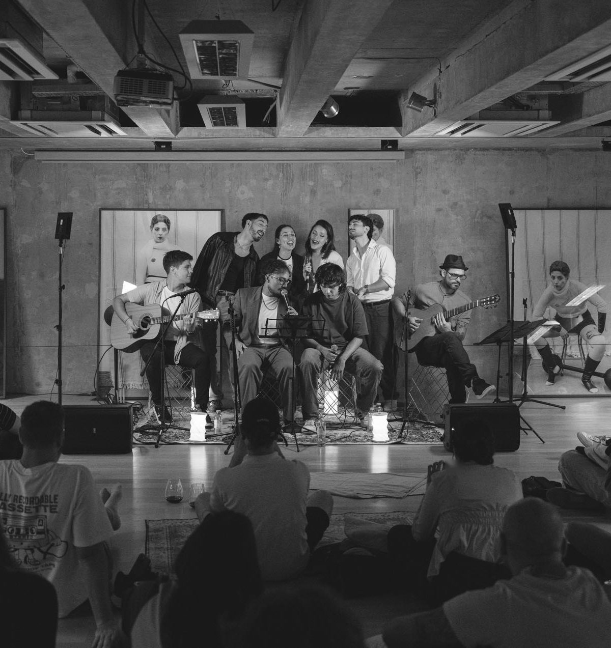 Show acústico con el público sentado en el piso, mirando a los músicos