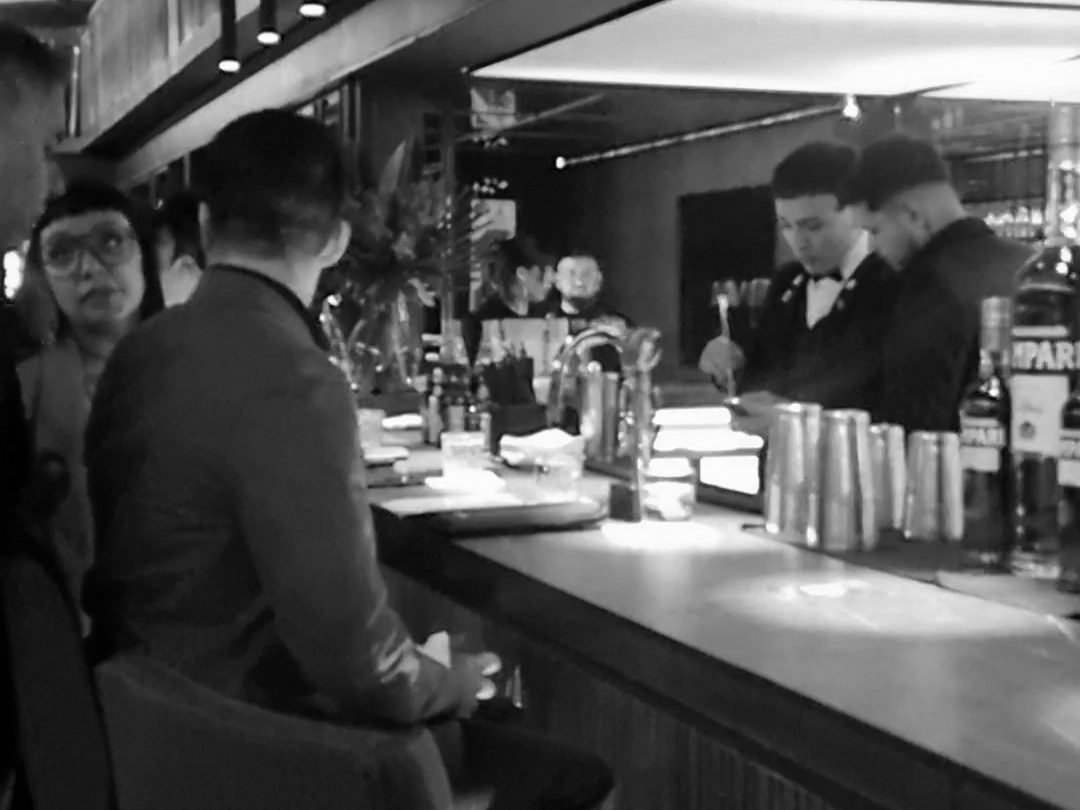 Barra de un bar con bartenders preparando tragos